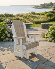 White Adirondack chair on a stone patio with a scenic view of water and greenery.