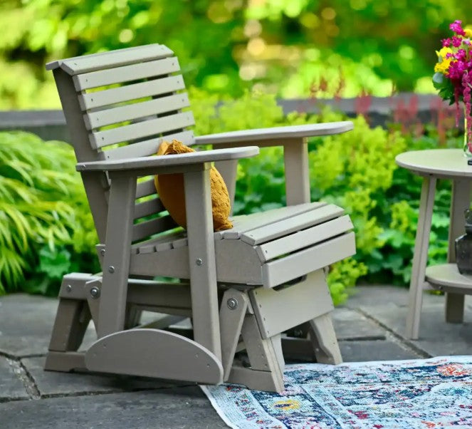 Side view of glider chair with orange pillow on stone patio
