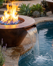 Close up image of the Mesa Hammered Copper Fire & Water bowl on a stone ledge next to a pool.  