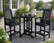 Sequoia 36" bar table in black with two Sequoia bar height chais on a stone patio decorated with lush plants and flowers.  