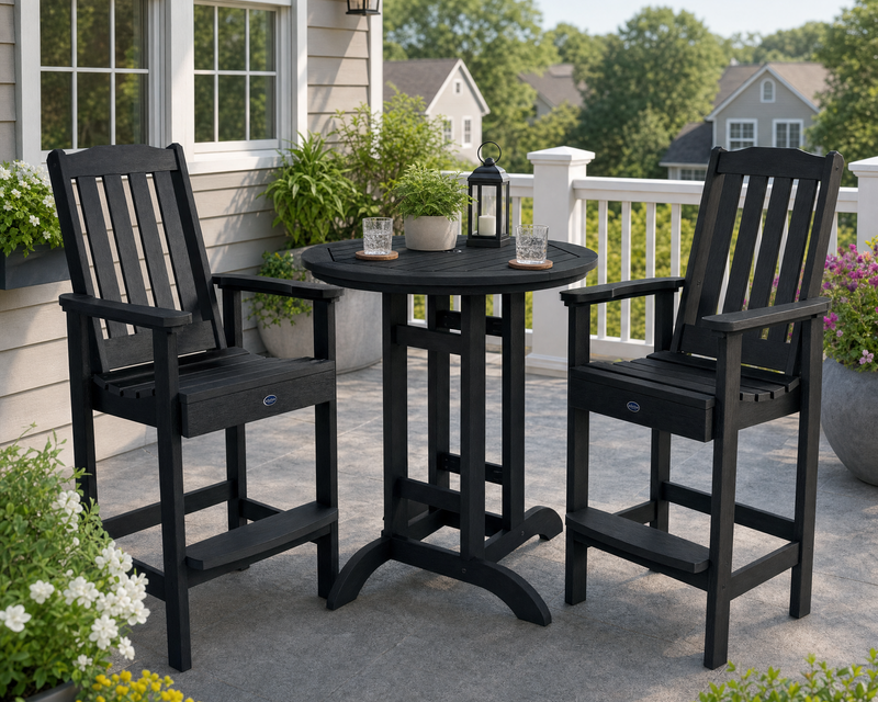 Sequoia 36" bar table in black with two Sequoia bar height chais on a stone patio decorated with lush plants and flowers.  