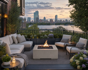 Alea 40 inch clay concrete fire pit with black lava rocks centered in a seating area on a patio of a brownstone in Boston with views of the city.