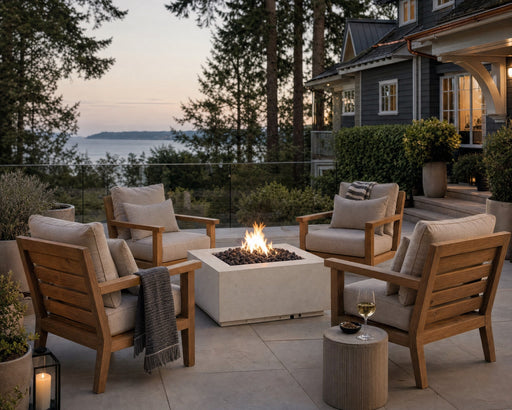 Alea 40-inch limestone concrete fire pit on a stone patio surrounded by teak seating and potted plants near a lake home with lake views.  