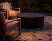 HPC 48 inch black aluminum fire pit cover on a fire pit placed on a stone patio with teak seating.  