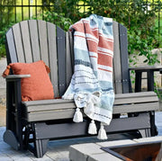Gray glider with a striped blanket and orange pillow in an outdoor setting.
