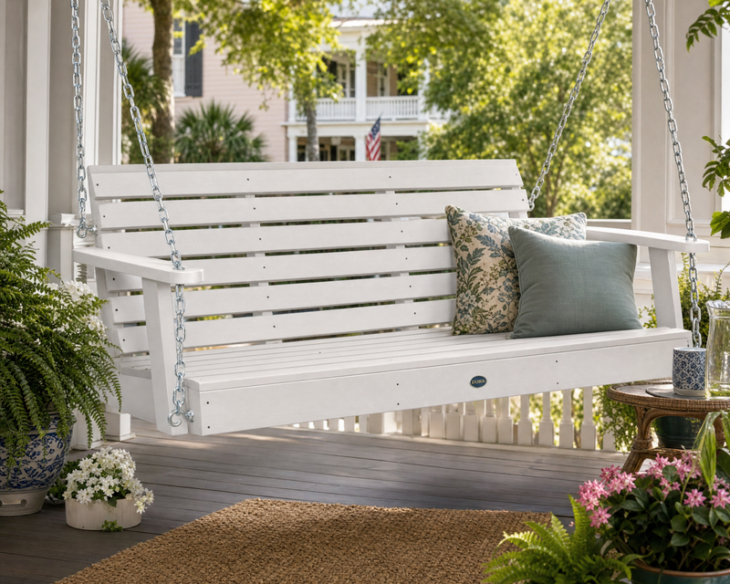 Sequoia 5' porch swing in white on a porch with a neutral rug and pillows and lush plants and flowers.  
