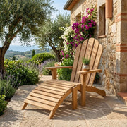 Anderson Teak Adirondack chair with Ottoman on stone patio by a stone house with lush gardens and flowing vines.  
