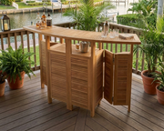 Anderson Teak Altavista Folding Bar Table on a wooden patio overlooking a intercoastal scene and views of a waterway.  