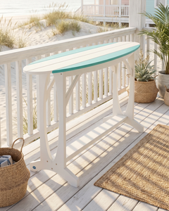 White table with a blue accent stripe on a wooden deck with beach view.