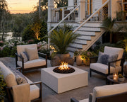 Bravo 32-inch natural concrete fire pit on a stone patio centered amongst a seating area with southern marsh views, lush plants and flowers.  