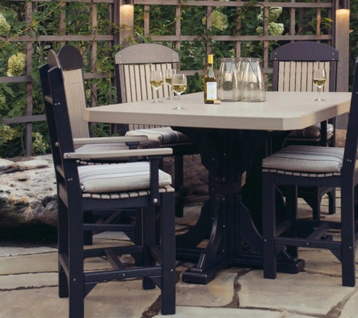 A 5-piece outdoor dining set featuring a square light beige table and four black chairs with light beige slatted backs and striped cushions, set on a stone patio in front of a wooden trellis.