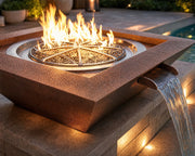 Close up view of the Sedona 40-inch hammered copper fire and water bowl nesting beside a pool on a stone patio.  