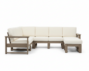 An outdoor sectional sofa set with cream-colored cushions and a weathered taupe-brown frame, including a three-seat section, a chaise lounge, and a matching ottoman, shown on a solid white background.