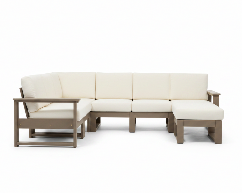 An outdoor sectional sofa set with cream-colored cushions and a weathered taupe-brown frame, including a three-seat section, a chaise lounge, and a matching ottoman, shown on a solid white background.