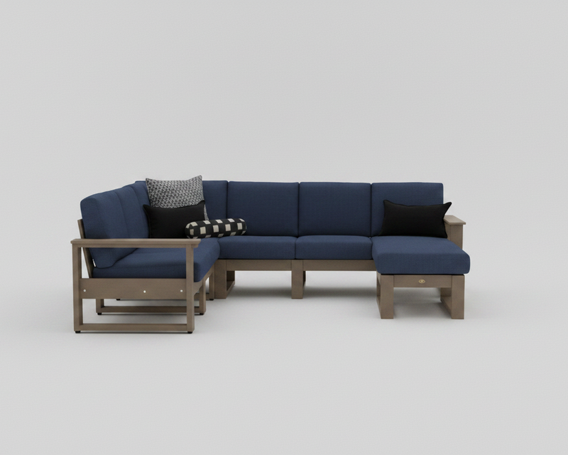 A modern outdoor sectional sofa set with navy blue cushions and a light brown wood frame, styled with three decorative throw pillows on a neutral gray background.