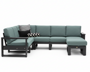 An outdoor sectional sofa set with a left-facing chaise lounge, a three-seat section, and a right-facing ottoman, upholstered in a muted teal fabric with a dark charcoal frame. Two decorative throw pillows are placed on the left side: one solid black and one black and white checkered.