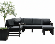 A modern outdoor sectional sofa set in dark charcoal gray with black wooden frames, including a chaise lounge, matching ottoman, side table, and black-and-white patterned accent pillows, shown against a plain white background with a potted tree on the left.