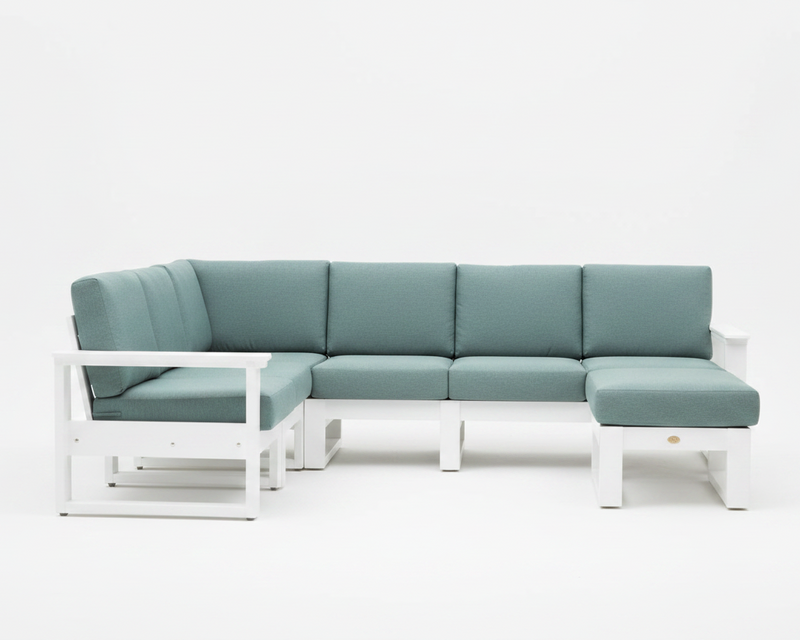 A modern outdoor sectional sofa with a white frame and sage green cushions, shown against a seamless white studio background.
