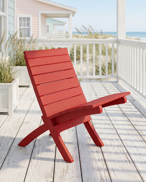 Red chair on a wooden deck with a beach house and ocean view in the background