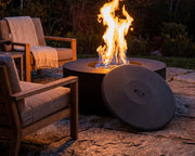 HPC 48-inch aluminum fire pit cover resting next to an aluminum fire pit on a stone patio with teak seating.  