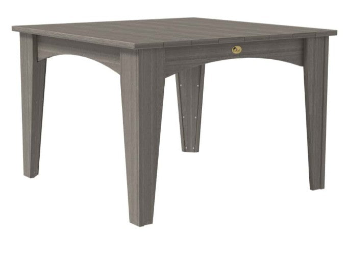 A square dining table in a weathered gray finish, featuring a small brass lock on the front apron, set against a plain white background.