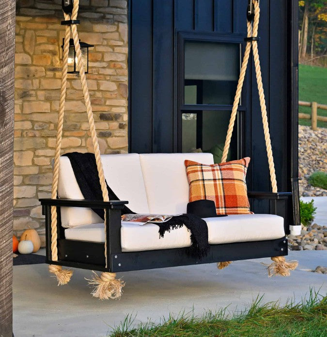 Black swing with white cushions and plaid pillow on a porch.