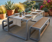 Anderson Teak Monza dining table with 2 3-seater benches on a stone patio overlooking the ocean.  
