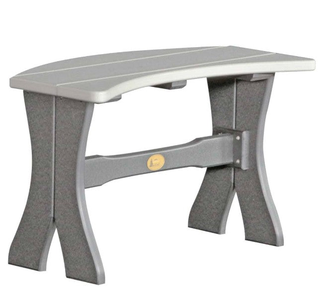 A gray outdoor bench with a curved seat and textured legs, featuring a small gold circular emblem on the center support beam, shown against a plain white background.