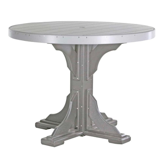 A round outdoor dining table with a distressed silver-gray finish, featuring a slatted top and a decorative pedestal base with rivet details.