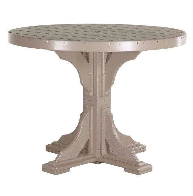 A round outdoor dining table with a slatted top and a sturdy pedestal base, finished in a warm taupe-beige color, shown against a plain white background.