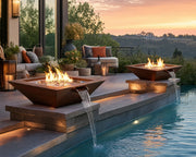 HPC Sedona 40-inch hammered copper fire and water bowls nesting beside an inground pool on a stone patio with a seating area and soft lighting.  