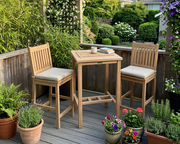 Anderson Teak Avalon 3-piece bar set on a wooden patio with flowers.  