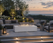 Sonoma 56-inch natural concrete fire pit on a stone patio seating area with views of a lake in the distance.  