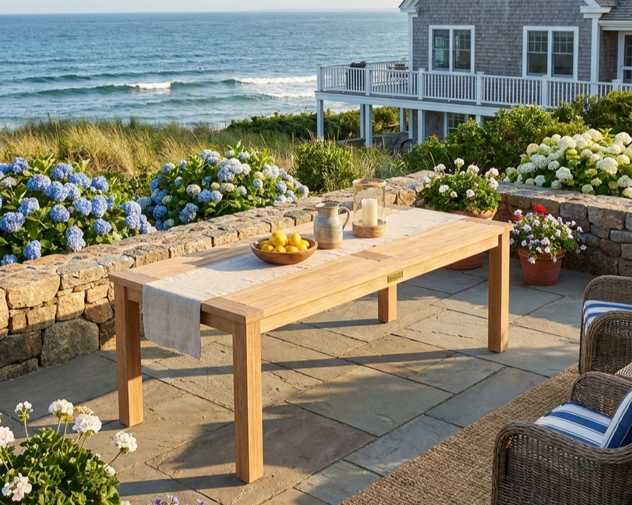 Anderson Teak Bahama rectangular coffee table on a stone patio overlooking the ocean.