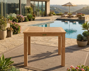 Anderson Teak 35" Bistro Table set on a rug on a stone patio overlooking a pool with Canyon views.  