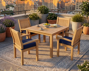 Anderson Teak 47 inch square dining table with four Sahara dining chairs with navy cushions.  The dining set is on a neutral colored run on a stone terrace overlooking the city.