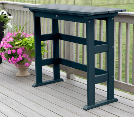 Blue outdoor bar table on a wooden deck with pink flowers in the background
