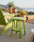 Green outdoor chair and table set with potted plants on a patio with a scenic background.