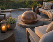 HPC hammered copper cover on a Mesa 32-inch fire bowl sitting on an elevated stone patio with teak seating, plants and candles.  