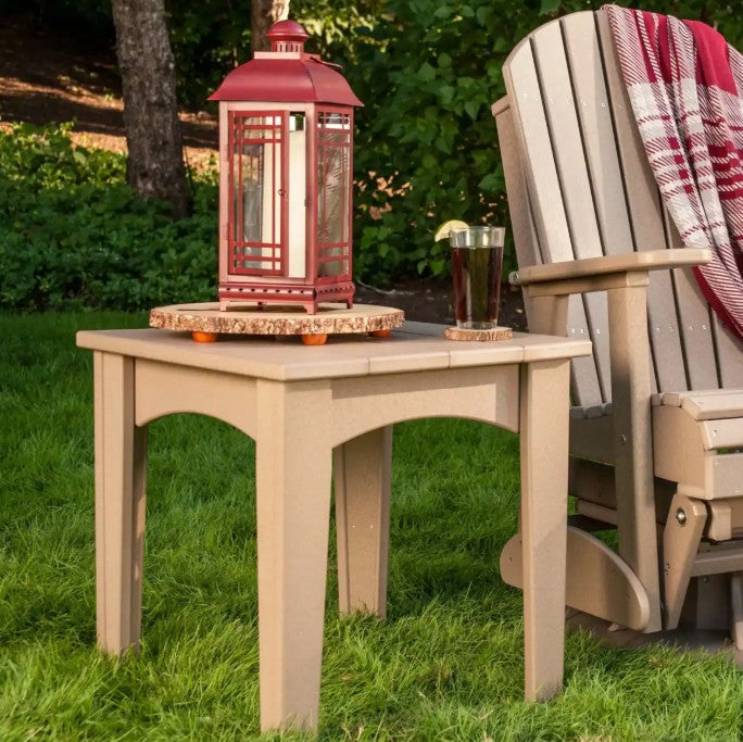 Island end table next to an Adirondack chair on a grass lawn .  