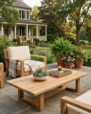Anderson Teak Junus coffee table on stone patio with deep seting chairs and views of a southern home.  