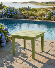 Green outdoor table by a pool with flowers and natural scenery