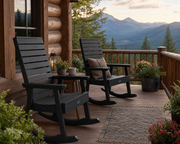Two Sequoia rocking chairs in black on a wooden porch of a log cabin home in the mountains.  The porch is decorated with potted plants and flowers.  