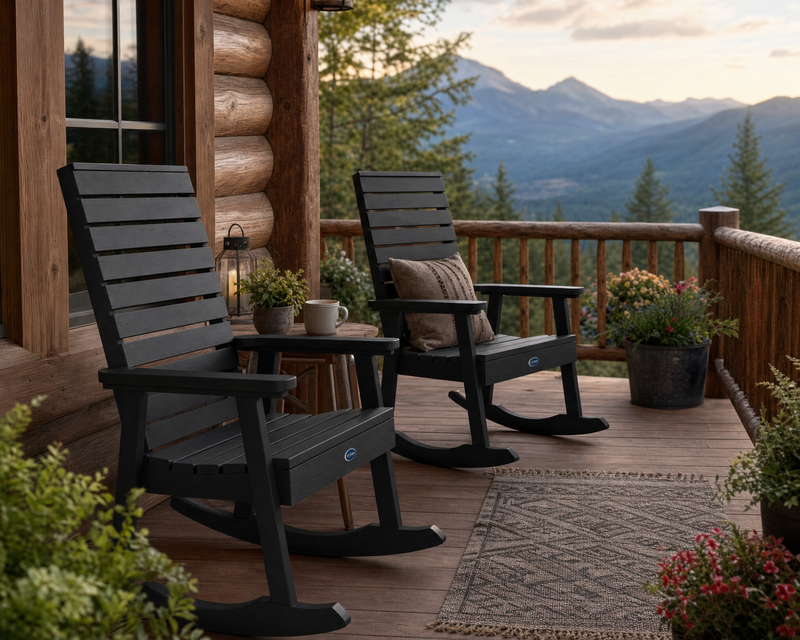 Two Sequoia rocking chairs in black on a wooden porch of a log cabin home in the mountains.  The porch is decorated with potted plants and flowers.  