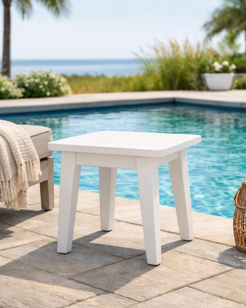 White outdoor table by a pool with a scenic background