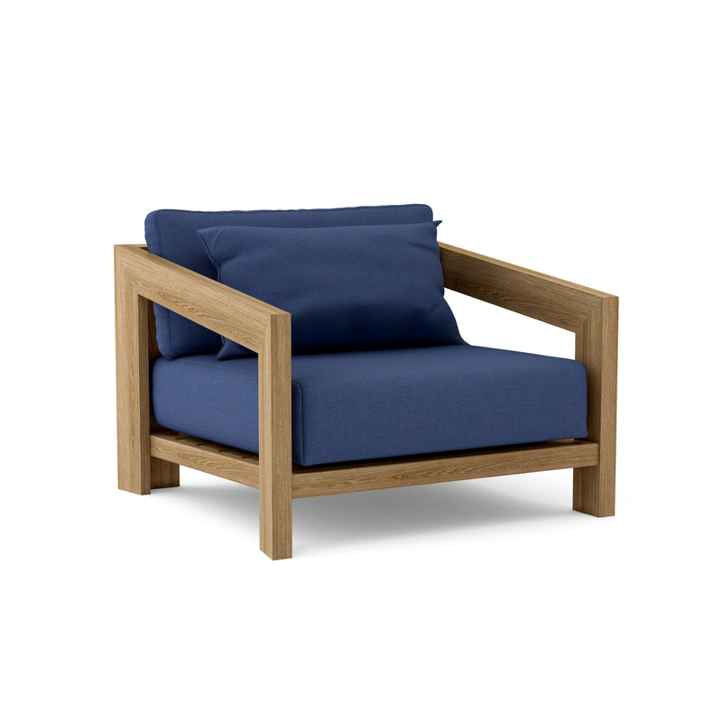 Smyrna teak lounge chair with navy cushion on white background.  