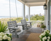 Two Sequoia single seat swings in coastal teak on a porch near the coast with ocean views. 

