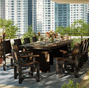 An outdoor dining set on a balcony, featuring a rectangular dark table surrounded by matching armchairs and a floral arrangement in the center.